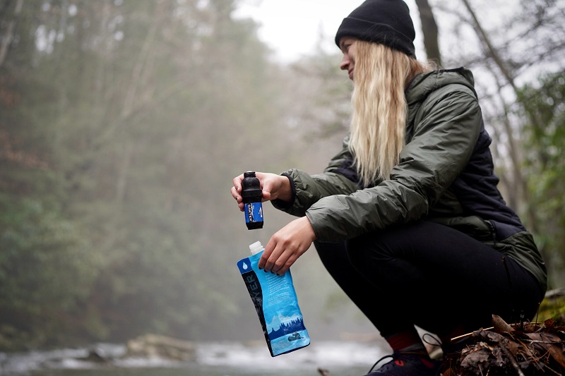 Woman holding squeeze water filter in nature