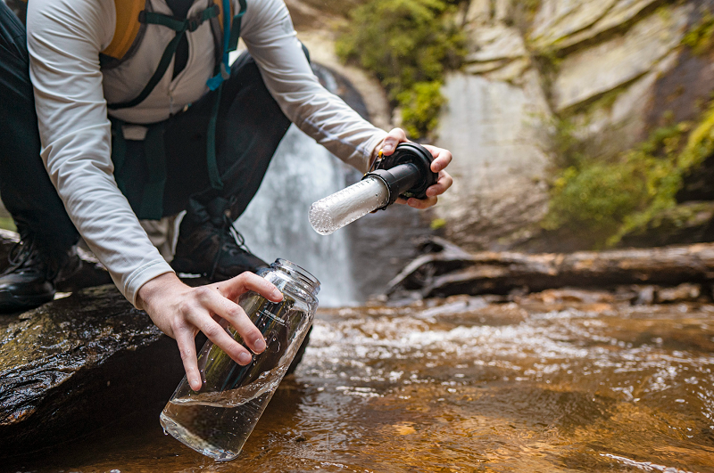 Man holding bottle water filter in nature